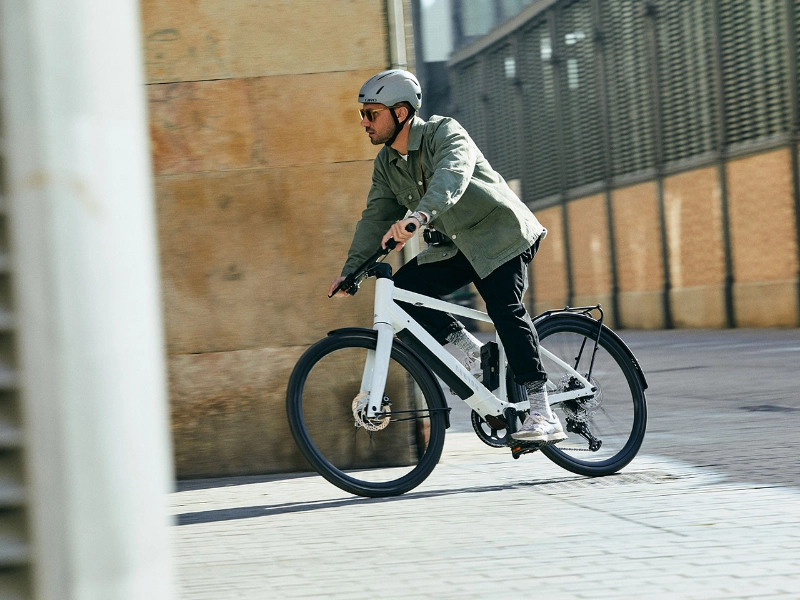 Radfährer fährt mit einem weißen Canyon um eine Straßenecke Radfährer fährt mit einem weißen Canyon um eine Straßenecke